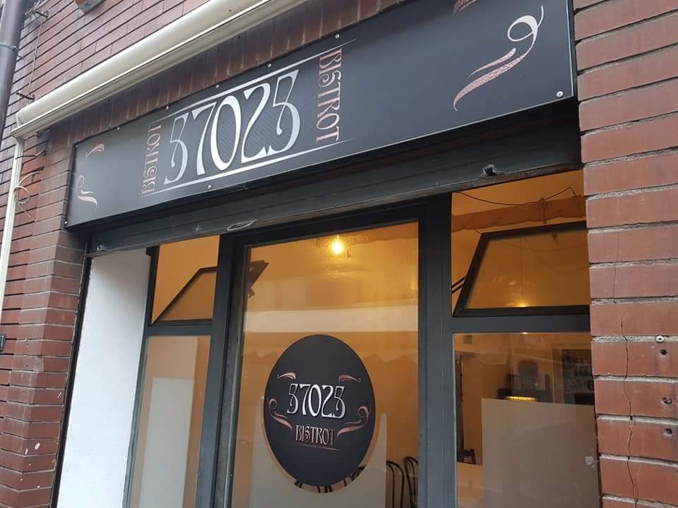 L&rsquo;ingresso del 57025 Bistrot in Via Andrea Costa: insegna scura con la scritta 57025 Bistrot e il tondo sulla vetrata.