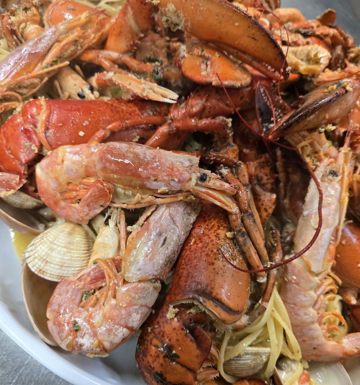 Un grande piatto di linguine ai frutti di mare con astice, scampi, gamberi e vongole, servito al 57025 Bistrot.